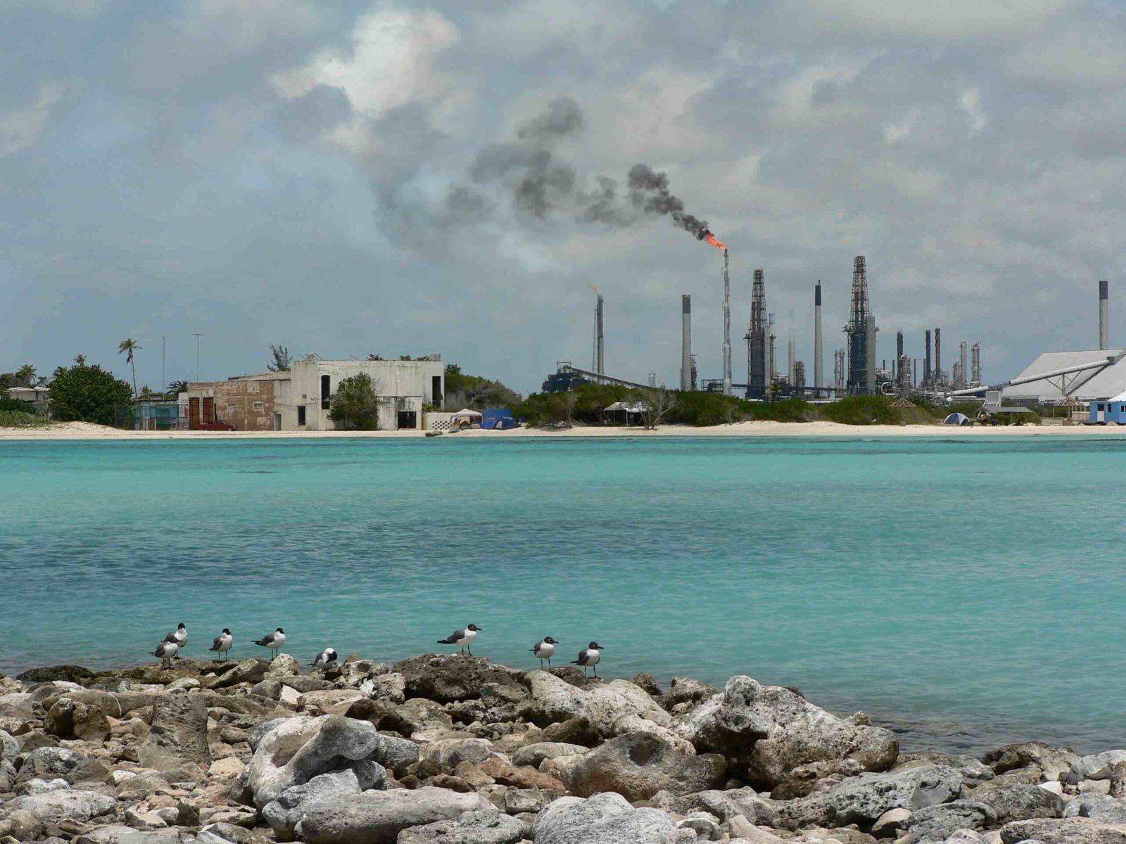 Valero Ölraffiniere von einem Karibikstrand aus fotografiert Kontrast Energieerzeugung Tourismus